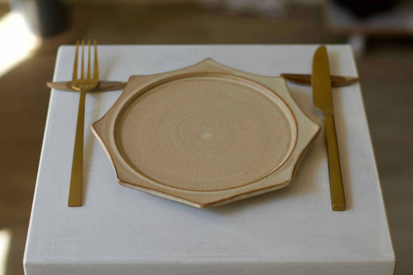 Wooden plate with gold fork and knife on a white surface