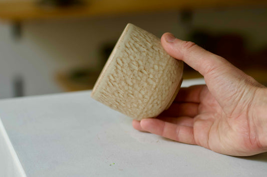 Hand holding a textured ceramic cup