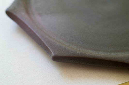 Close-up of a dark gray ceramic plate on a light surface