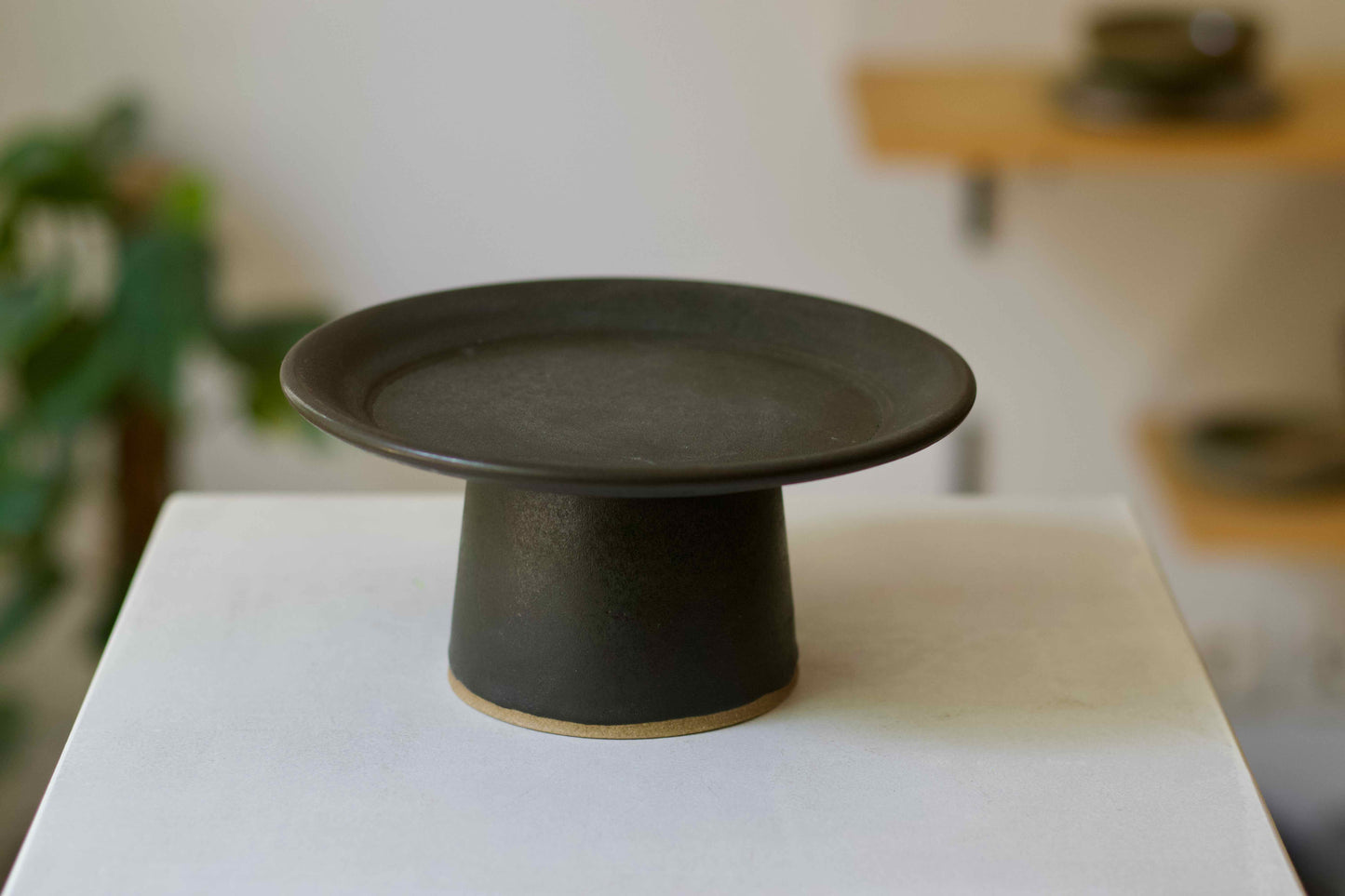 Black ceramic pedestal on a white surface with a blurred background