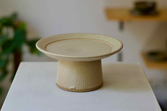 Ceramic cake stand on a white surface with a blurred background